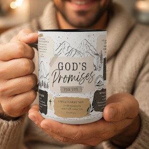 May include: A white ceramic mug with a black interior and handle, featuring a collage-style design with mountain illustrations, speckles, and text including "GOD'S Promises FOR YOU" and "I WILL CARRY YOU I will sustain you and I will rescue you."