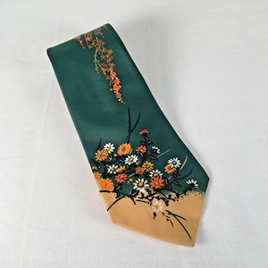 May include: A dark green tie with a floral pattern. The tie has a tan lower section with a bouquet of white, orange, and yellow flowers. A branch of orange flowers extends from the top. The tie is made of a smooth, shiny material.