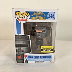 May include: A Funko Pop Movies vinyl figure of the Black Knight from Monty Python and the Holy Grail, number 246. The figure is inside a box labeled Black Knight [Flesh Wound] with an Entertainment Earth Exclusive sticker on the front.