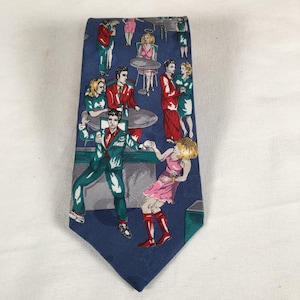 May include: A navy blue necktie featuring a repeating pattern of stylized figures in a nightclub setting. The figures are dressed in various outfits, with a color palette including red, green, and pink. The tie has a pointed end.