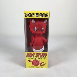 May include: A red Hot Stuff the Tuff Little Devil bobblehead figure inside a yellow and black Wacky Wobbler box. The character has small horns, a white diaper, and holds a red trident. The box features the character name and a graphic illustration.