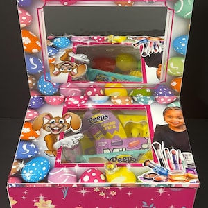May include: Pink Easter-themed gift box with a clear window showing a variety of items, including Peeps flavored lip balm, a yellow chick toy, and makeup brushes. The box is decorated with colorful Easter eggs and the name "Taliyah" is printed on the top.