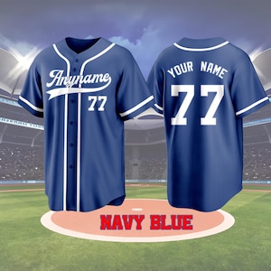May include: Navy blue baseball jersey with white accents. The front features the name "Anyname" and the number 77. The back displays "YOUR NAME" and the number 77. The jersey is displayed on a baseball field.