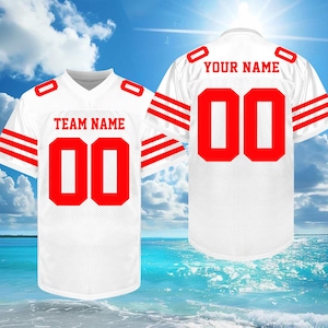 May include: White football jersey with red accents, including the number "00" on the front and back. The front displays "TEAM NAME" and the back says "YOUR NAME". The jersey has red stripes on the sleeves.