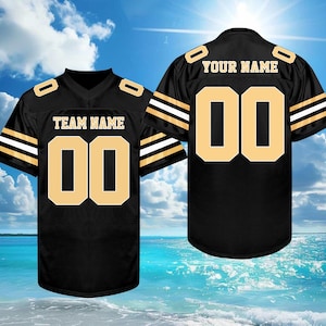 May include: Black football jersey with gold accents, featuring the number "00" on the front and back. The front displays "TEAM NAME", and the back says "YOUR NAME". The jersey has gold stripes on the sleeves.