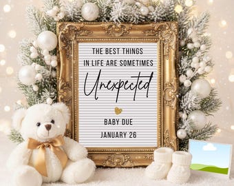 May include: A gold framed announcement board with the text "THE BEST THINGS IN LIFE ARE SOMETIMES Unexpected BABY DUE JANUARY 26". A white teddy bear with a gold bow sits next to the board, with white baby booties and decorative greenery.