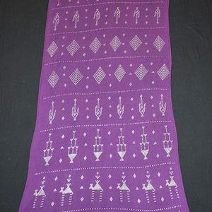 May include: A long, rectangular purple textile with a repeating pattern of white geometric and stylized human figures. The design includes diamonds, triangles, and dotted lines. The fabric appears to be a scarf or shawl.