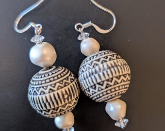 May include: A pair of dangle earrings with white and black patterned beads and clear crystal accents.