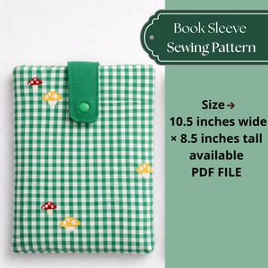 以下が含まれることがあります： 緑と白のギンガムチェックのブックカバー、キノコの刺繍入り。 スリーブには、ボタン留めの緑色のフラップが付いています。 画像のテキストは「Book Sleeve Sewing Pattern」と「Size -> 幅26.7cm x 高さ21.6cm 利用可能 PDF FILE」です。