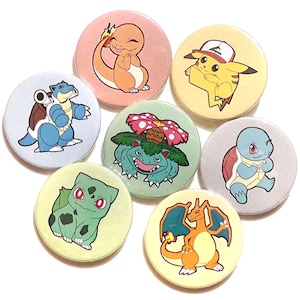 Może przedstawiać: Zestaw siedmiu okrągłych, kolorowych guzików z kreskówkowymi postaciami Pokemonów. Postacie to Bulbasaur, Charmander, Squirtle, Venusaur, Charmeleon, Blastoise i Pikachu.