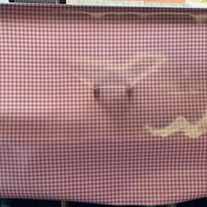 Puede incluir: Mantel de mesa a cuadros rojos y blancos con un ligero brillo. El mantel est&aacute; hecho de tejido tejido y tiene una textura suave.