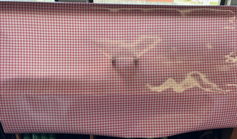Puede incluir: Mantel de mesa a cuadros rojos y blancos con un ligero brillo. El mantel est&aacute; hecho de tejido tejido y tiene una textura suave.
