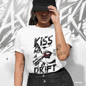 May include: A white t-shirt with a black and white graphic design of a woman's lips with lipstick and the text "Kiss My Drift".