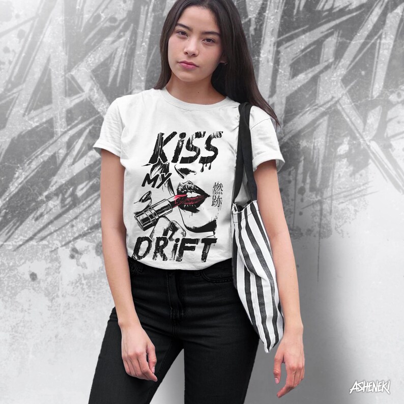 May include: White t-shirt with a black and white graphic print of a woman's lips with lipstick and the text "Kiss My Drift".