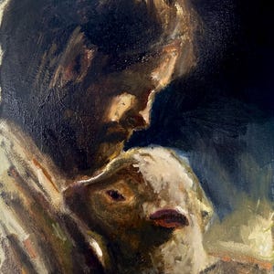 May include: An oil painting on canvas depicting a person with dark hair and a beard holding a small white lamb close to their chest. The artwork uses deep shadows and warm highlights to emphasize the figures against a dark, indistinct background.