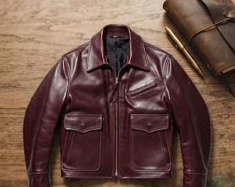 May include: A deep burgundy leather jacket featuring a classic collar, a full-length front zip, two large flap pockets on the lower front, and a single slanted chest pocket. The jacket has long sleeves with cuffs and a smooth, dark interior lining.