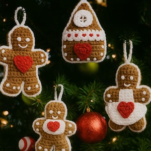 May include: Crocheted Christmas decorations featuring gingerbread men and a gingerbread house. The ornaments are brown with white detailing and red heart shapes. They hang from white loops against a green Christmas tree background.