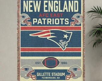 May include: A rectangular New England Patriots throw blanket. The blanket features the team's logo, helmets, and the words "New England Patriots" in white text on a blue background. Red and grey stripes and a football graphic are also present.