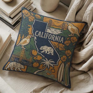 May include: Square throw pillow with a navy blue California state outline, featuring the Golden Gate Bridge, a bear, birds, oranges, and surfboards. The word "CALIFORNIA" is printed in white.