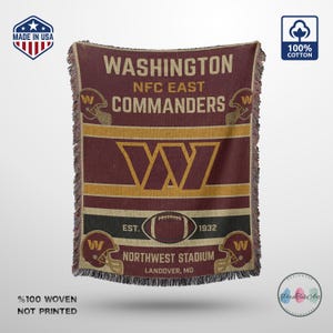 May include: A woven cotton throw blanket featuring the Washington Commanders logo, team name, and NFC East text in burgundy and gold. The design includes football helmet graphics, a central W logo, a football icon, and text reading EST. 1932.