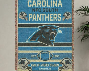 May include: Carolina Panthers throw blanket in blue, black, and beige. The blanket features the team name, logo, and established year. The text "Bank of America Stadium, Charlotte, NC" is also visible.