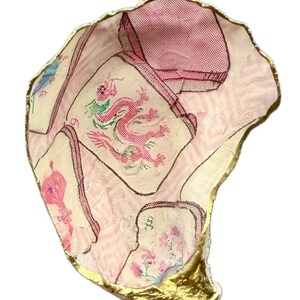 Puede incluir: Un plato decorativo de concha de ostra con un dise&ntilde;o de decoupage en patrones rosas y blancos, que incluye una ilustraci&oacute;n central de un drag&oacute;n rosa. Los bordes de la concha est&aacute;n pintados con un acabado dorado met&aacute;lico. El texto Style 3 es visible.