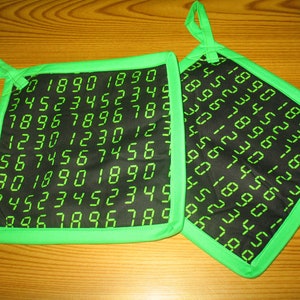 May include: Two green and black pot holders with a repeating pattern of green numbers on a black background. The numbers are in a digital font.