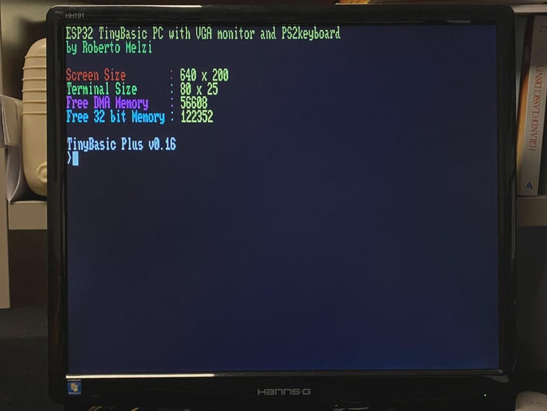 Puede incluir: Un monitor de computadora negro que muestra una interfaz de l&iacute;nea de comandos con texto en verde, rojo, morado y azul. La pantalla muestra informaci&oacute;n del sistema para una PC ESP32 TinyBasic, incluyendo tama&ntilde;o de pantalla y estad&iacute;sticas de memoria.