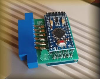 Puede incluir: Una pequeña placa de circuito azul y verde con un conector azul y una pequeña placa de circuito azul con un chip. La placa de circuito tiene una luz LED verde y varios pines.