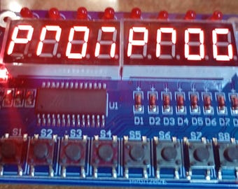 Puede incluir: Una placa de circuito azul con pantallas LED rojas que muestran "P00.8.888". Tiene botones, LEDs y el texto "LED & KEY". Probablemente para electrónica o programación.