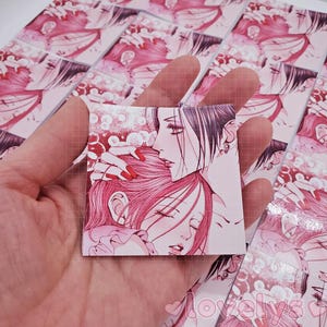 May include: A close-up of a pink and white anime illustration of two characters. The character on the left has long pink hair and is wearing a white dress. The character on the right has long black hair and is wearing a black dress. The characters are embracing each other.