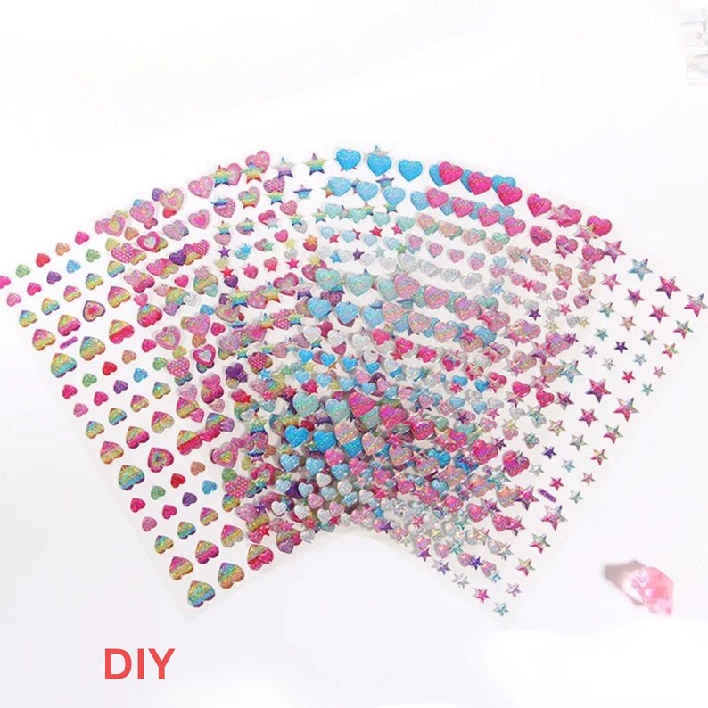 May include: A set of colorful, iridescent, adhesive sheets with hearts and stars. The sheets are transparent and have a glittery finish. The text "DIY" is printed on the bottom of the image.