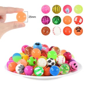 May include: A collection of colorful bouncy balls with various designs, including smiley faces, watermelons, and glitter. The balls are 25mm in diameter and are displayed on a white plate.