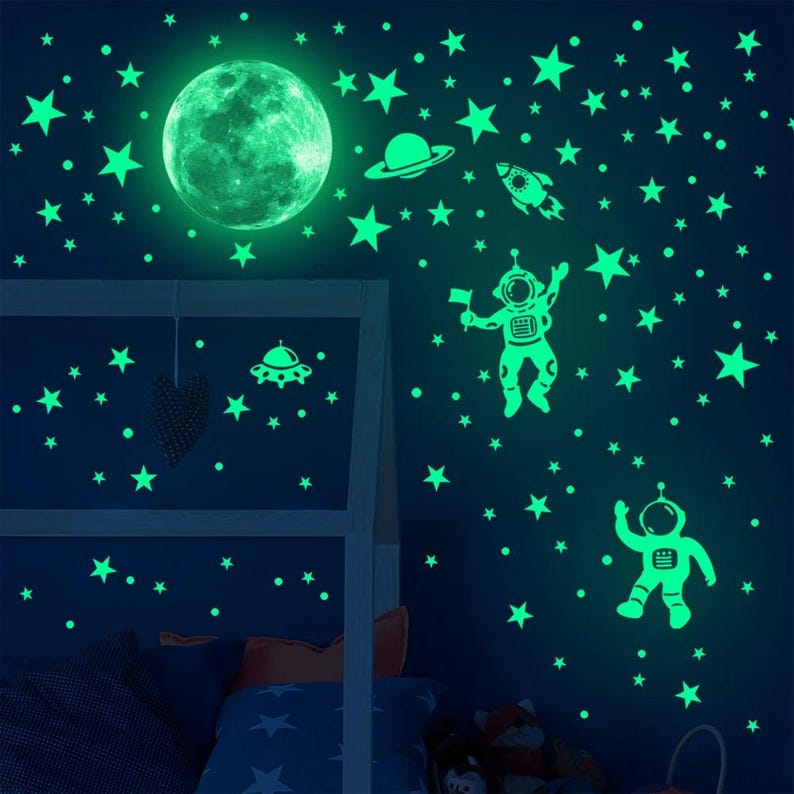 K&ouml;nnte beinhalten: Leuchtende Wandaufkleber mit einem Mond, Sternen, einer Rakete, einem Raumschiff und zwei Astronauten. Die Aufkleber sind perfekt f&uuml;r ein Kinderzimmer oder einen Spielraum.