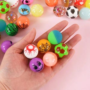 May include: A variety of colorful bouncy balls with different designs, including a watermelon, a spiderweb, an eye, a smiley face, and a soccer ball.