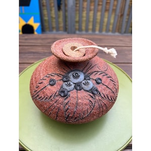 May include: A white ceramic mug with a black handle and the text "But First, Coffee" in a black, handwritten-style font. The mug is on a white surface.