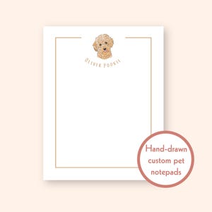 以下が含まれることがあります： 上部に犬の手描きイラストが入った、薄茶色の縁取りの白いメモ帳。犬は薄茶色で、下に「Oliver Pookie」という名前が書かれています。右下には「手描きのカスタムペットメモ帳」というテキストが入ったピンク色の円があります。