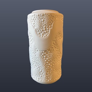 May include: A white ceramic mug with a black handle and the text "But First, Coffee" in a handwritten style. The mug is on a white surface. The mug is approximately 10 cm tall.