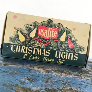 May include: Vintage Christmas lights box with the text "CHRISTMAS LIGHTS" and "8 Light Series Set." The box features a festive design with illustrations of lights, pine needles, and a red ribbon. The brand name "usalite" is displayed prominently.
