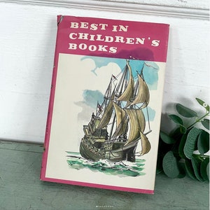 May include: A vintage book titled "Best in Children's Books" with a pink cover and a watercolor illustration of a ship with sails on the ocean.