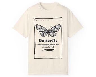 May include: A beige t-shirt with a black and white graphic of a butterfly. The graphic includes the word "Butterfly" and the text "transformation, rebirth, and personal growth".