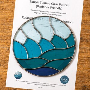 May include: A circular stained glass pattern titled Simple Stained Glass Pattern (Beginner Friendly) featuring a wave design in shades of light blue, teal, and dark blue. The paper includes numbered sections, a glass cutter, and The Hope Anthology logo.