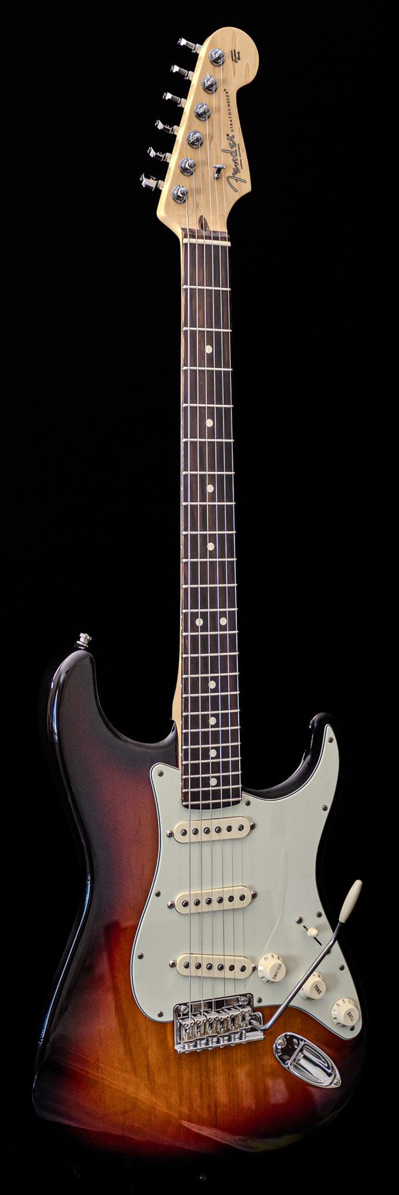 Pu&ograve; includere: Una chitarra elettrica Fender Stratocaster con finitura sunburst. La chitarra ha un manico in acero, battipenna bianco e tre pickup single-coil. Il logo Fender &egrave; sulla paletta.