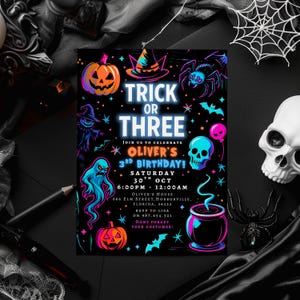 May include: A black Halloween-themed invitation with neon illustrations of a pumpkin, witch's hat, spider, ghost, skull, and cauldron. The text reads "Trick or Three" and invites guests to Oliver's 3rd birthday on October 30th.