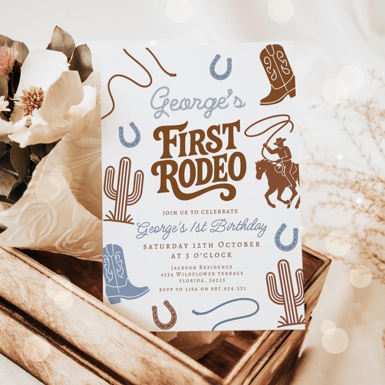 May include: A white invitation card with a cowboy theme. The text reads "George's First Rodeo" with illustrations of a cowboy on a horse, boots, cacti, and horseshoes. The invitation is for George's 1st birthday.
