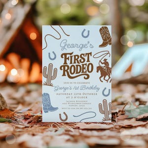 May include: A light blue invitation card with a rodeo theme. The card features illustrations of cowboy boots, cacti, horseshoes, and a cowboy on a horse. Text includes "George's First Rodeo" and birthday details.
