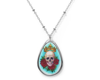 May include: A silver chain necklace with a teardrop-shaped pendant featuring a white skull with a gold crown and red roses on a turquoise background.