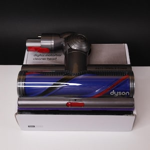 May include: A Dyson digital motorbar cleaner head, featuring a silver and gray design with red accents. The cleaner head has a blue and red roller brush and the Dyson logo. The text "digital motorbar cleaner head" is visible.