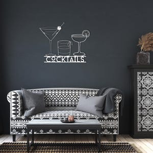 Peut inclure: D&eacute;coration murale en m&eacute;tal blanc repr&eacute;sentant un verre &agrave; martini, un verre &agrave; whisky et un verre &agrave; cocktail avec le mot "Cocktails" en dessous.