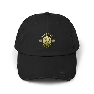 May include: Black distressed baseball cap with a curved brim. The cap features a gold logo with the text "VIROQUA ARONIA EST. 2024". The cap has a pre-worn, vintage look.